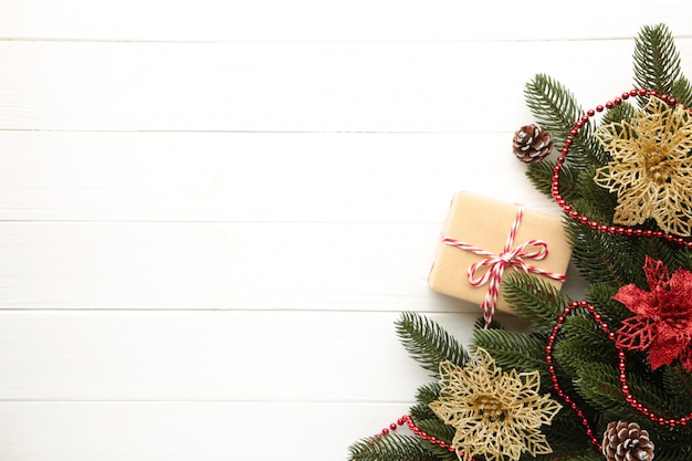 Decoración navideña. Rama de abeto con regalo y flores de navidad rojas y doradas sobre fondo blanco