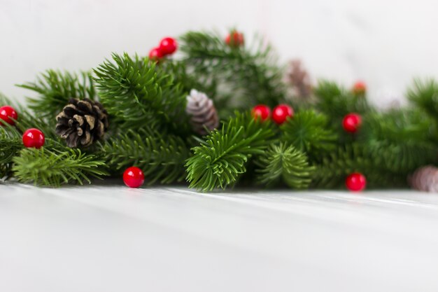 Decoración navideña Ramas de abeto con conos y frutos rojos sobre un fondo blanco.