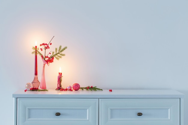 Decoración navideña rosa con velas encendidas en interior blanco