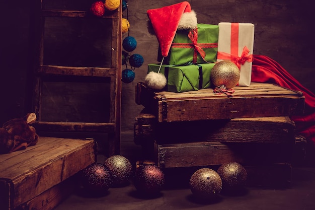 Foto decoración navideña con sombrero de papá noel, bolas deslumbrantes y cajas de regalo.