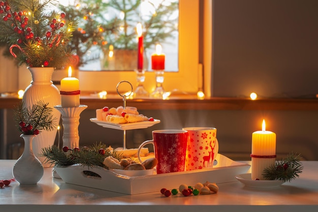 Decoración navideña y tazas rojas con bebida caliente en la cocina.