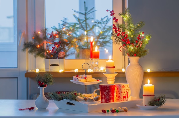 Decoración navideña y tazas rojas con bebida caliente en la cocina.