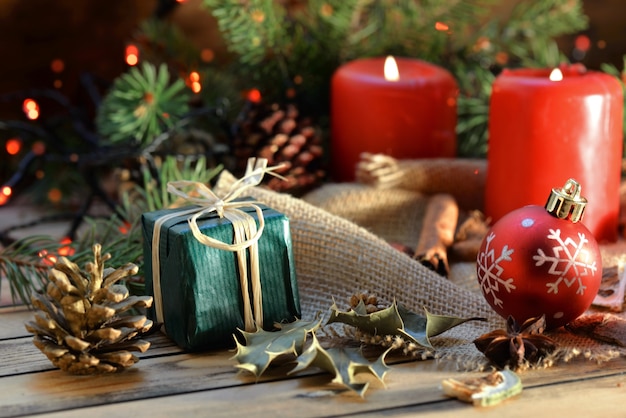 Decoración navideña tradicional en mesa de madera con velas y regalos en luces borrosas