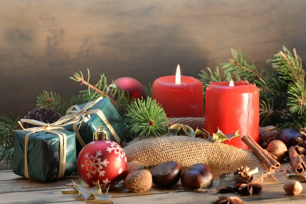 Decoración navideña tradicional sobre fondo de madera con velas y regalos