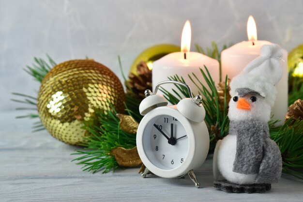 Decoración navideña de velas, ramas de abeto, despertador y pingüino