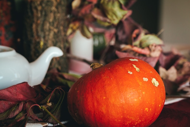 Decoración otoñal con velas de calabaza y vajilla.