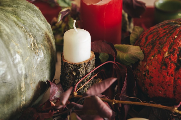 Decoración de otoño con calabaza, velas y vajilla.