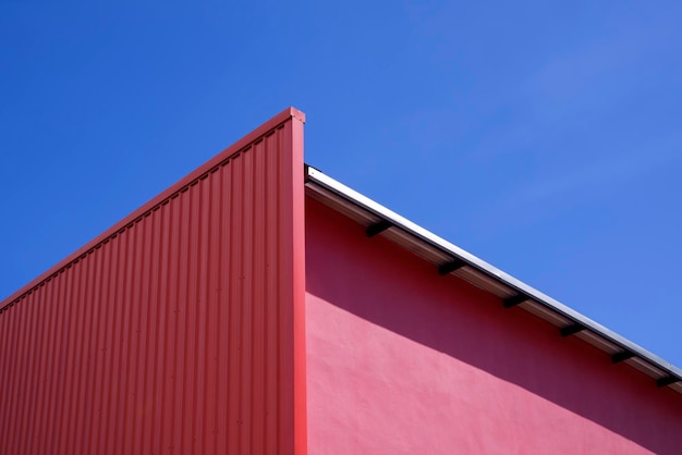 Decoración de pared de acero corrugado rojo vacío en la pared rosa de un edificio moderno contra el cielo azul claro