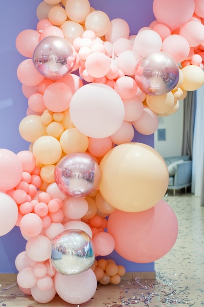 Decoración de pared con globos de colores Globos rosas, naranjas y blancos sobre un fondo morado