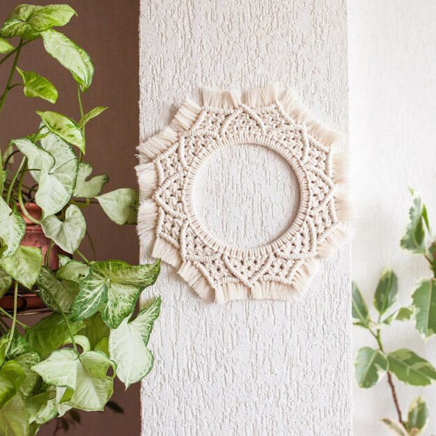 Foto decoración de pared de mandala de macramé de algodón colgando en la pared blanca con hojas verdes guirnalda de macramé hecha a mano hilo de algodón natural decoración ecológica para el hogar