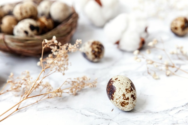 Decoración de Pascua con huevo en nido y algodón sobre mesa de mármol blanco