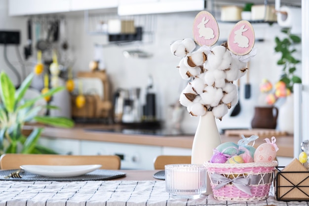 Decoración de Pascua de huevos coloridos en una canasta y un conejo en la mesa de la cocina en un estilo rústico Interior festivo de una casa de campo