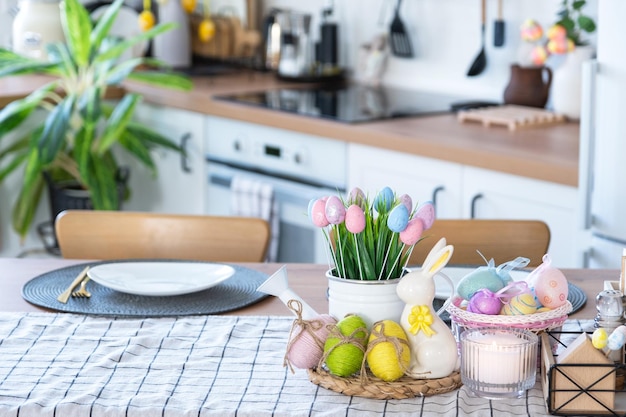 Decoración de Pascua de huevos coloridos en una canasta y un conejo en la mesa de la cocina en un estilo rústico Interior festivo de una casa de campo