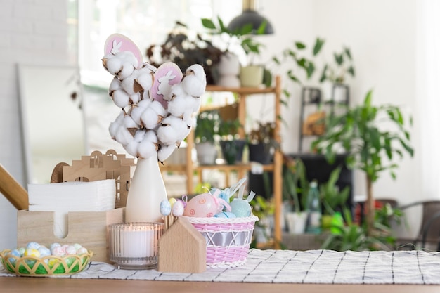 Decoración de Pascua de huevos coloridos en una canasta y un conejo en la mesa de la cocina en un estilo rústico Interior festivo de una casa de campo