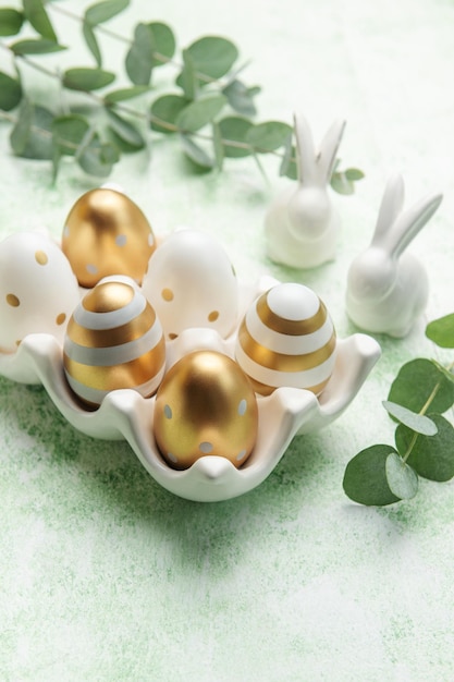 Decoración de Pascua Huevos de Pascua dorados en un soporte de cerámica y conejos decorativos