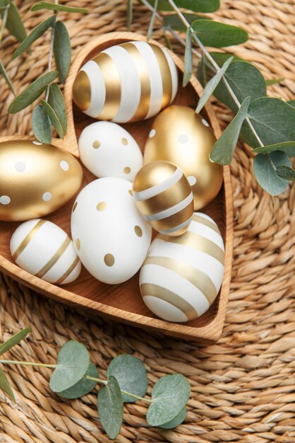 Decoración de Pascua Huevos de Pascua pintados en oro en un cuenco de madera en forma de corazón