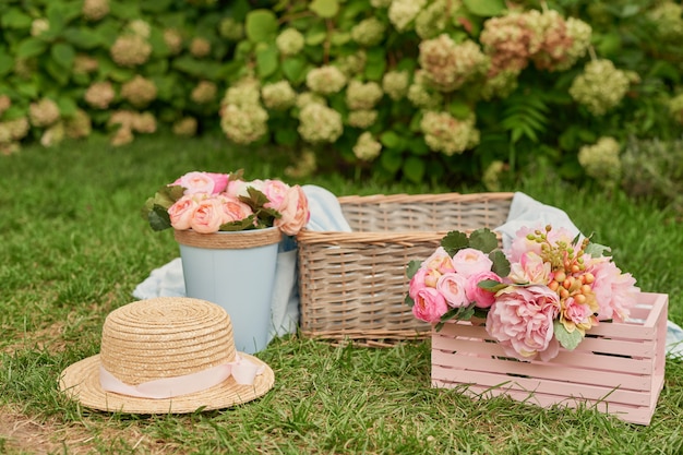 decoración de picnic con flores rosas, una canasta y un sombrero en el césped en el verano en el jardín