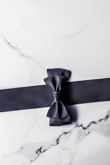 Decoración de regalo de vacaciones y promoción de venta concepto cinta de seda negra y lazo sobre fondo de mármol f ...