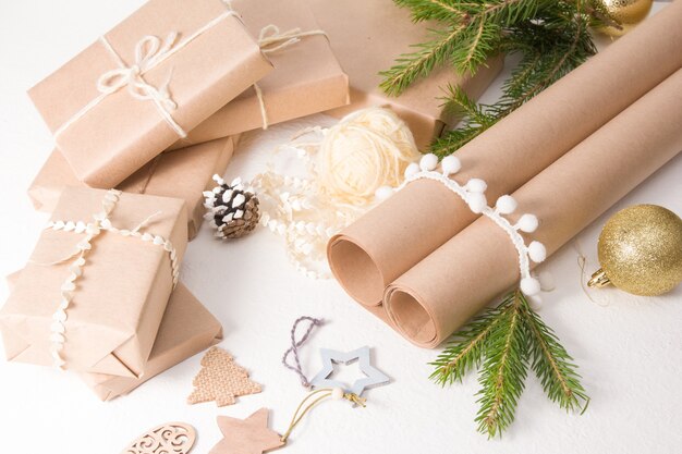 Decoración de regalos navideños en estilo ecológico, papel para embalaje, decoración con materiales naturales y cajas de regalo sobre un fondo blanco, decoración casera para Navidad y año nuevo.