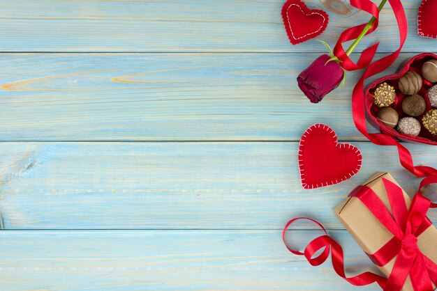 Foto decoración romántica del día de tarjetas del día de san valentín con las rosas y el chocolate en una tabla de madera azul.