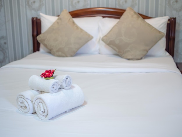 Decoración de toallas blancas limpias con flor roja en una cama blanca limpia en la habitación del hotel