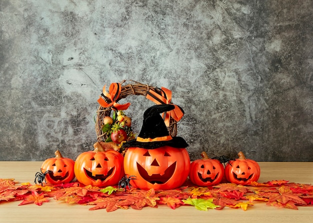 Decoración de vacaciones de Halloween con linterna de cabeza de calabaza y hojas de otoño en la mesa de madera con fondo de muro de hormigón, concepto de fondo de halloween, espacio de copia.