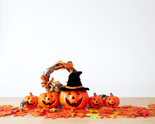 Decoración de vacaciones de Halloween con linterna de cabeza de calabaza y hojas de otoño en la mesa de madera con fondo de pared blanca, concepto de fondo de halloween, espacio de copia.