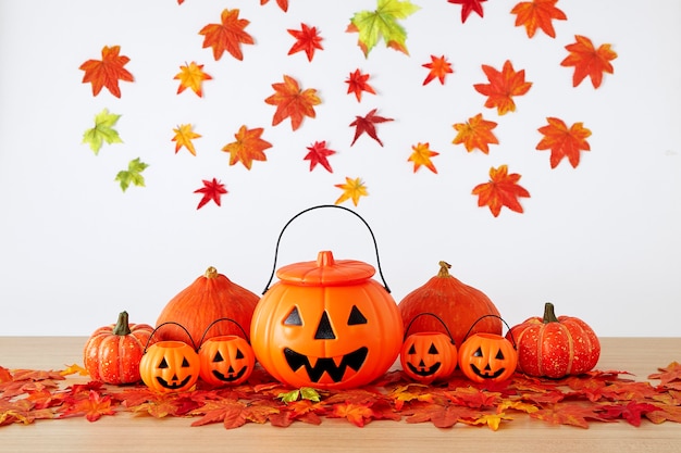 Decoración de vacaciones de Halloween con linterna de cabeza de calabaza y hojas de otoño en la mesa de madera con fondo de pared de hojas blancas, concepto de fondo de halloween, espacio de copia.