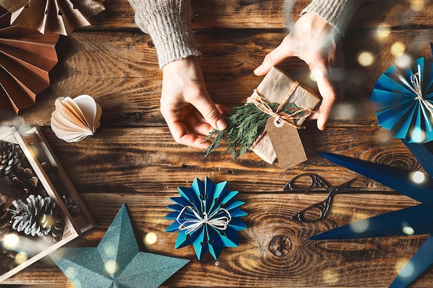 Decoración de vacaciones de invierno manos de mujeres haciendo regalos de Navidad papel copos de nieve estrellas y fans