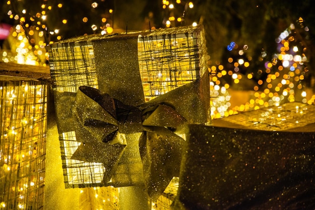 Decoración para vacaciones navideñas. Caja de regalo de oro bajo el árbol de Navidad en el concepto de plaza de la ciudad