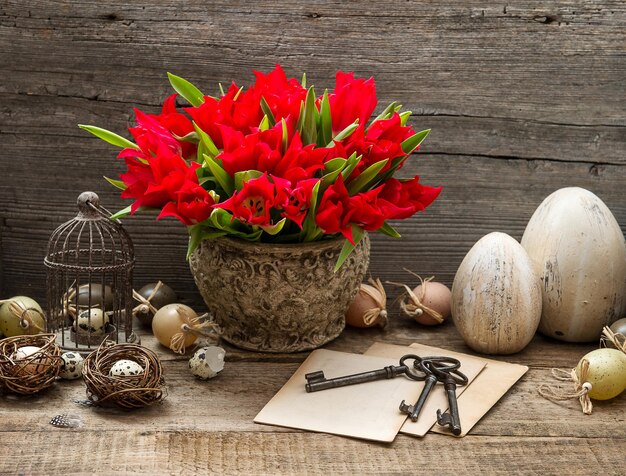 Decoración vintage de Pascua con jaula, huevos y flores de tulipanes rojos. interior de una casa de estilo rural