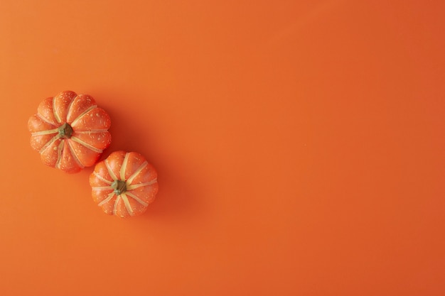 Decoraciones de calabazas sobre papel naranja.