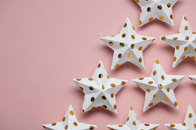 Decoraciones de estrellas blancas y doradas sobre un fondo festivo de temporada rosa pastel