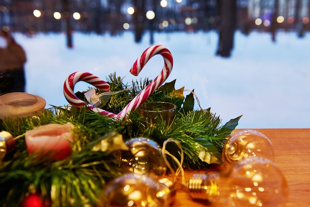 Decoraciones de navidad. Adorno en un árbol de Navidad con bastones de caramelo y velas con luces sobre un fondo cubierto de nieve. Vista desde la ventana.