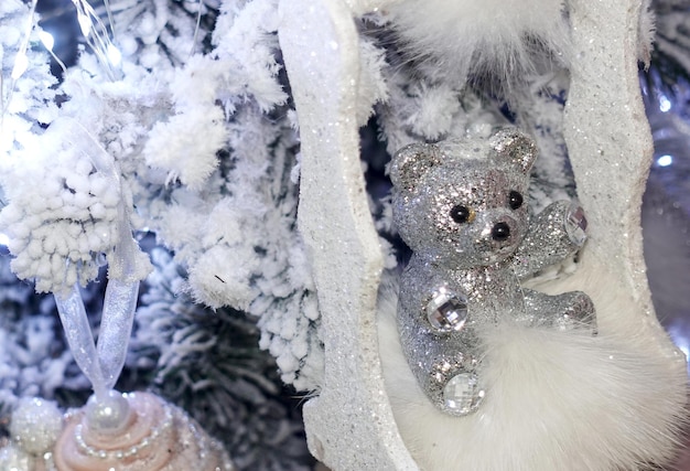 Foto decoraciones de navidad bonitas oso de peluche plateado en un árbol de navidad cubierto de nieve