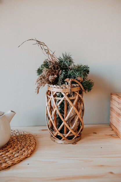 Decoraciones de navidad. Cesta con ramas de abeto en la mesa de madera. Decoraciones de mesa festivas. Decoración navideña escandinava.