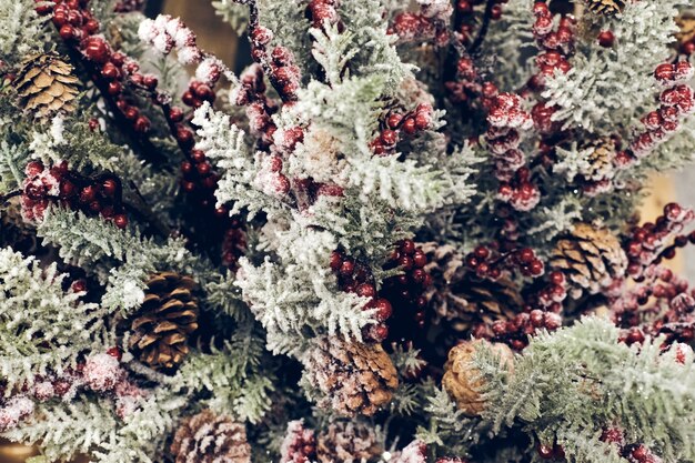 Decoraciones navideñas. Brunch de árbol de abeto de Navidad con frutos rojos y conos en la nieve brillante textura de cerca. Enfoque superficial. Concepto de papel tapiz de Navidad