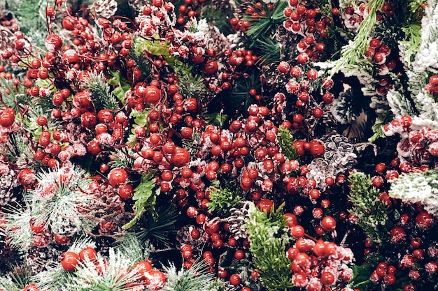 Decoraciones navideñas. Brunch de árbol de abeto de Navidad con frutos rojos y conos en la nieve brillante textura de cerca. Enfoque superficial. Concepto de papel tapiz de Navidad