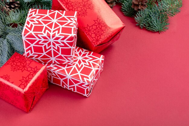 Decoraciones rojas de Navidad, ramas de abeto con cajas de regalo de juguetes en rojo