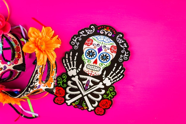 Decoraciones para la tradicional fiesta mexicana del Día de los Muertos sobre un fondo rosa.