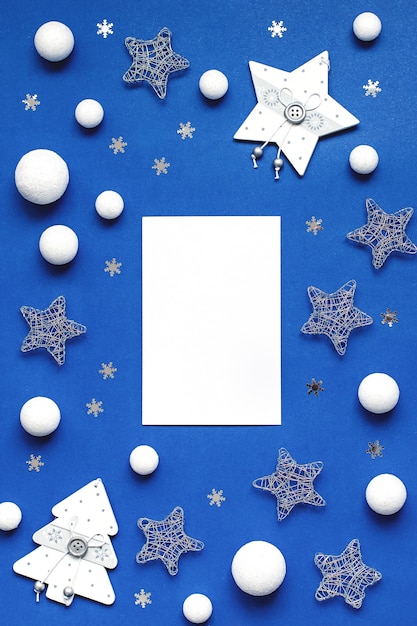 Decorações brancas e prateadas planas sobre fundo azul clássico com espaço de cópia. Plano de fundo de Natal na cor clássica azul com enfeites de prata e branco, plano de fundo de Natal com lista de desejos