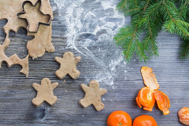 Decorações de Ano Novo e Natal em uma superfície de madeira com tangerinas e uma árvore de Natal Prepare doces em forma de biscoitos de gengibre e pão de gengibre para a celebração do Natal