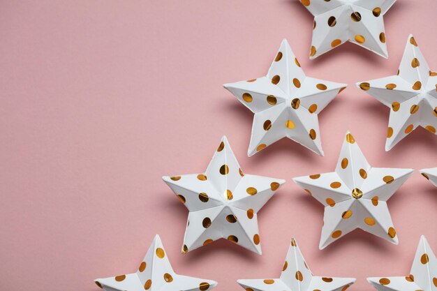 Decorações de estrelas brancas e douradas em um fundo festivo sazonal rosa pastel