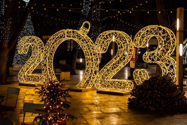 Decorações de feliz ano novo com grandes números 2023 Iluminação noturna festiva da cidade Conceito de celebração de Natal Ano novo 2023 imagem para cartão de felicitações