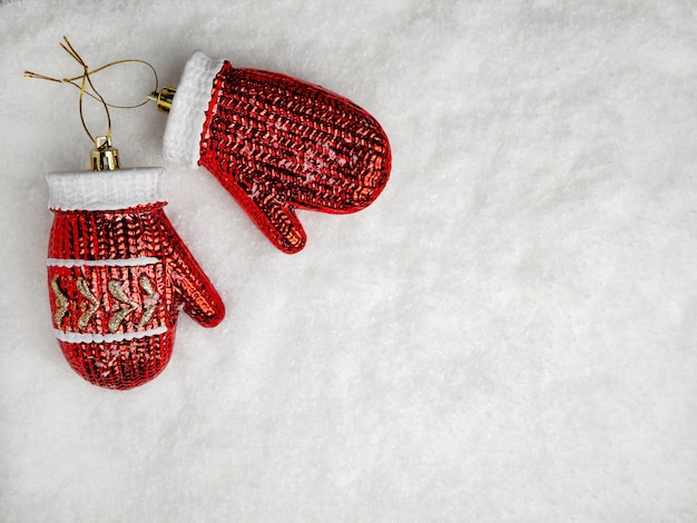 Decorações de férias. Luvas vermelhas do brinquedo da árvore de Natal de vidro na neve. O conceito de Natal com espaço de cópia
