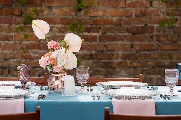 Decorações de mesa de flores para férias e jantar de casamento. Mesa posta para recepção de casamento no restaurante ao ar livre.