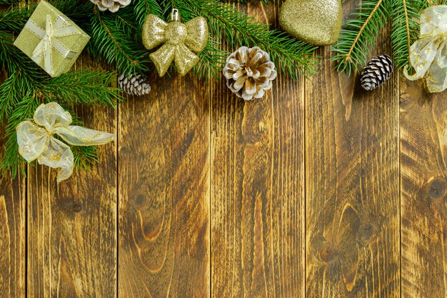 Decorações de Natal, bolas de cor dourada e pinhas sobre uma mesa de madeira marrom. Vista superior, copie o espaço.