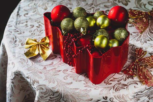 Foto decorações de natal de cor vermelha e dourada em uma caixa vermelha na forma de uma árvore de natal na mesa