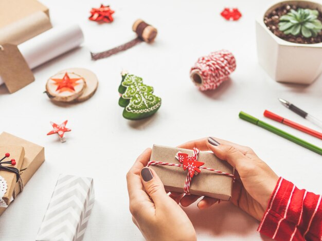 Foto decorações de natal de mesa branca mulher envolve presente de ano novo em papel artesanal espírito de férias de inverno