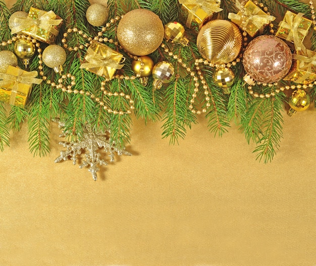 Foto decorações de natal douradas em um galho de abeto em um fundo dourado